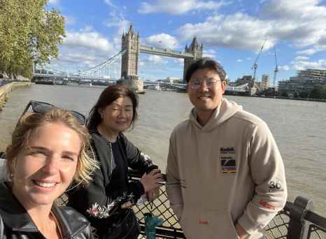 Three people standing by the River Thames with Tower Bridge in the background.