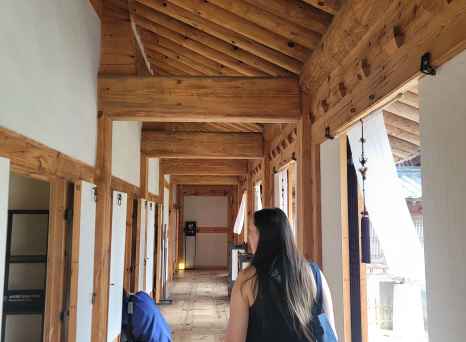 View of a person carrying a bag through a wooden corridor.