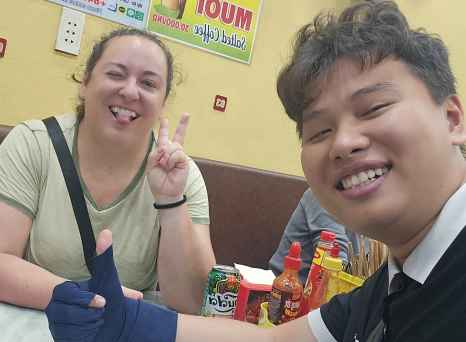 Woman and man posing for a selfie inside a small eatery.