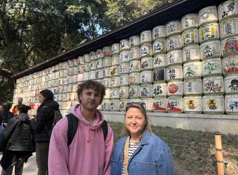 Visitors at Meiji Shrine with traditional sake barrels visible.