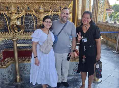 Three people standing in front of ornate architecture at the Grand Palace, Bangkok.