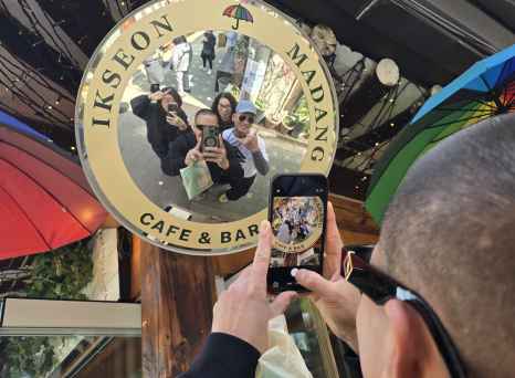 People taking a selfie in a circular mirror at Madang Ikseon Cafe.
