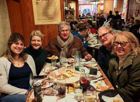 Diners gathered around a table in a cozy Bologna restaurant, food and beverages visible.