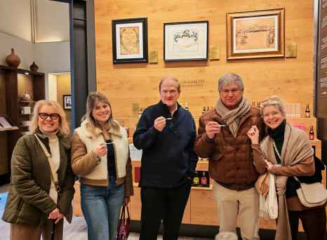 Group of visitors holding tasting spoons in a vinegar shop in Bologna.