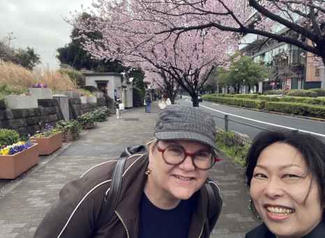 People posing on a path with blossoming cherry trees in the background.