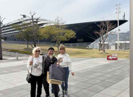 A happy trio poses by an impressive ship in Nagasaki.