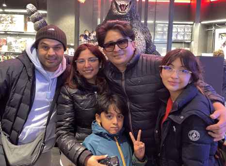 A cheerful group poses with a Godzilla figure in Tokyo.