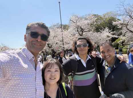 Friends gather under blooming trees, smiles bright in the sunlight.