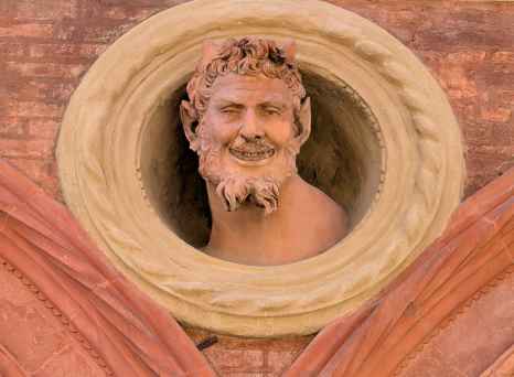A mischievous stone face peers from Bologna's intricate brickwork.