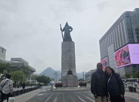 Strolling past a towering monument in Seoul's bustling heart.