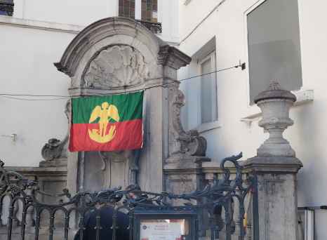 A colorful flag drapes over a historic fountain in Brussels.