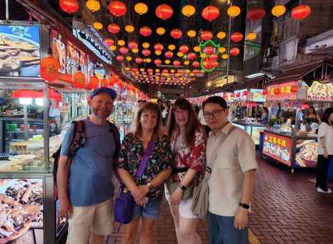Strolling under vibrant lanterns in a lively Hong Kong street market.