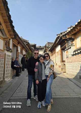 Three people stand on a traditional street in Seoul.