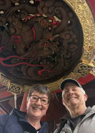 Two people standing under a large red lantern at Senso-ji Temple, Tokyo.