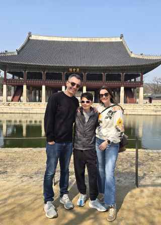 Family posing in front of Gyeonghoeru Pavilion at Gyeongbokgung Palace, Seoul.
