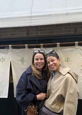 Two people standing in front of a restaurant with Japanese signage.