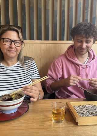 Two people dining at a Japanese restaurant table with soba noodles.