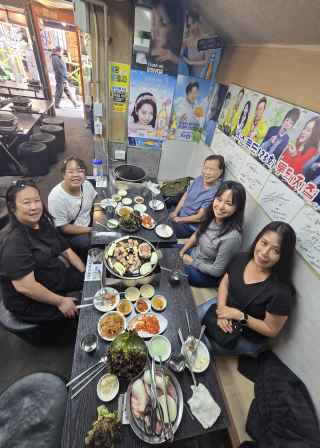 Group dining at a Korean barbecue restaurant with various dishes on the table.