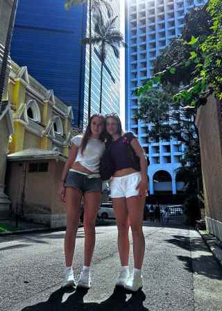 Tourists strolling under the skyscrapers in Hong Kong's midday sun.