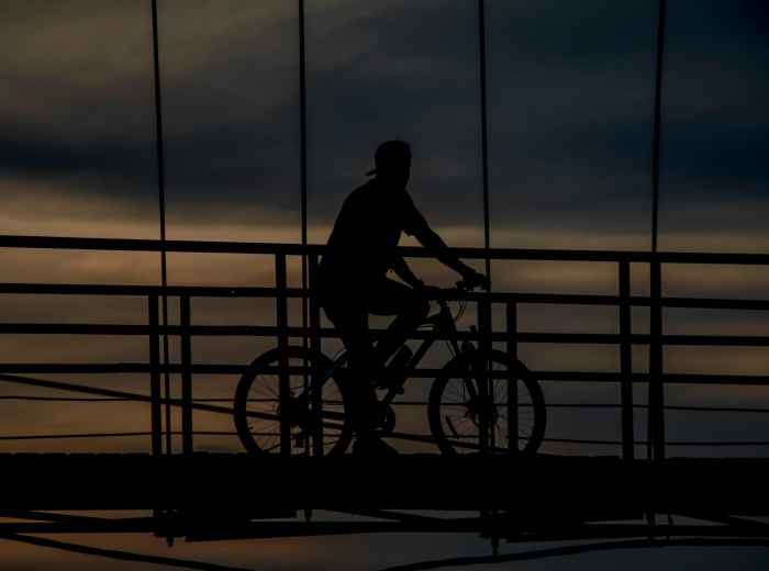 Cyclist crossing bridge at dusk photo Photo by alfian Pexels