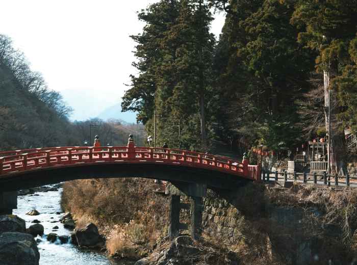 The iconic red arched bridge at Sumiyoshi Taisha reflected in the shrine’s pond, with a few locals quietly paying respects and no crowds in sight. Photo by wei on Unsplash