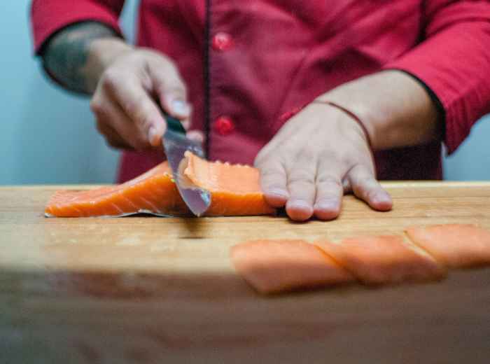 Students in a traditional sushi making class learning proper knife techniques from a local chef, with fresh fish and ingredients arranged on wooden cutting boards Photo by Juan Manuel Núñez Méndez on Unsplash
