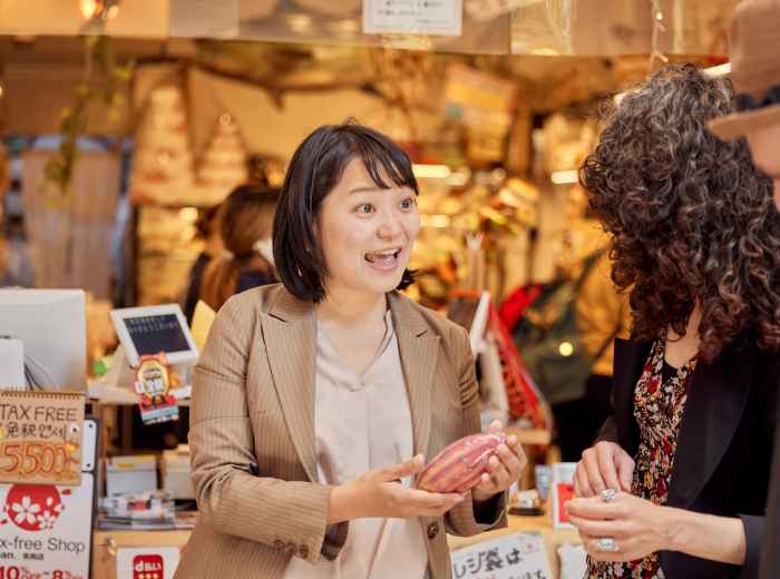Host guiding small group through market pointing out seasonal ingredients.