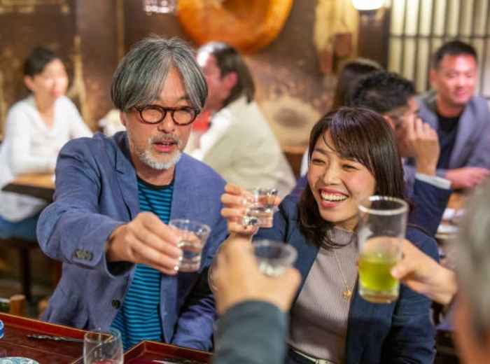 Craft beer and sake glasses mid-toast between guests. Image by davidf