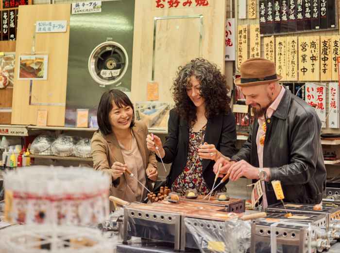Small group gathered at street stall sampling food.