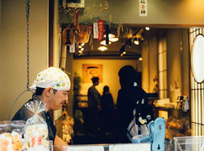 A craftsperson at work while visitors watch respectfully. Photo by Andrew Leu from Unsplash