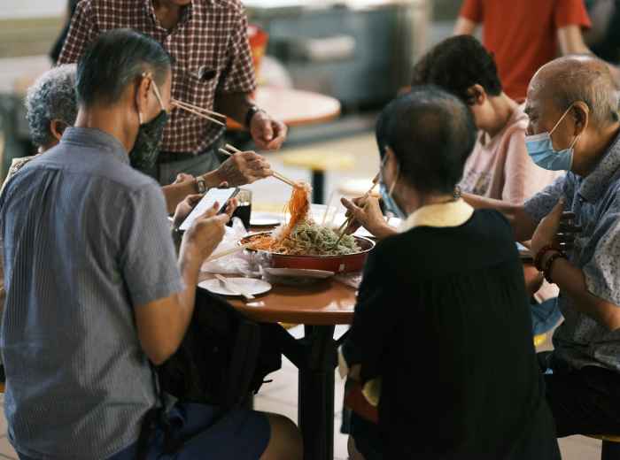A multi-generational family sharing a meal at a casual restaurant near Osaka Station, with the local host helping facilitate conversation and ordering. Image by Galen Crout on Unsplash.