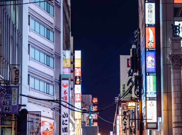 Street-level view of Dotonbori at night with crowds of people and restaurant signs
