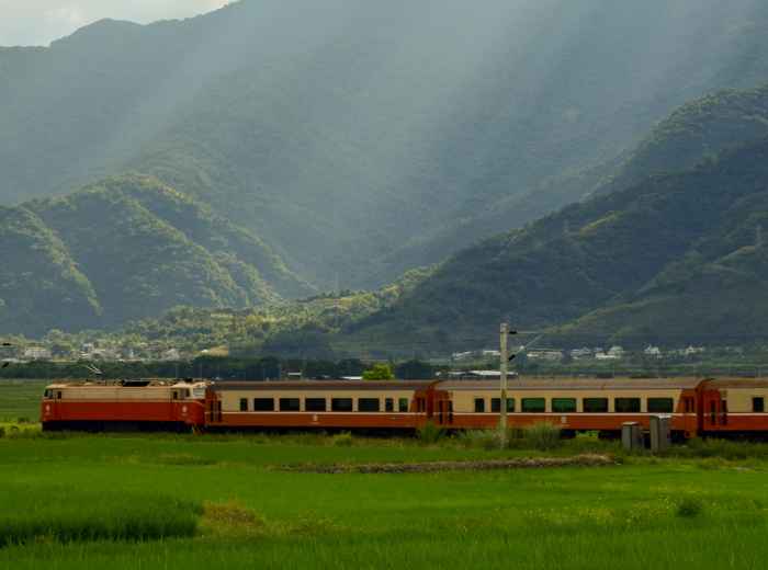 Traditional train traveling through Japanese countryside with mountains in background Photo by Tseng Shiya on Unsplash