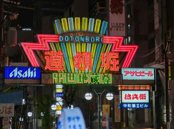 Entrance to Janjan Yokocho lit by colorful blinking neon signs at night. Image by Haoli Chen on Unsplash.