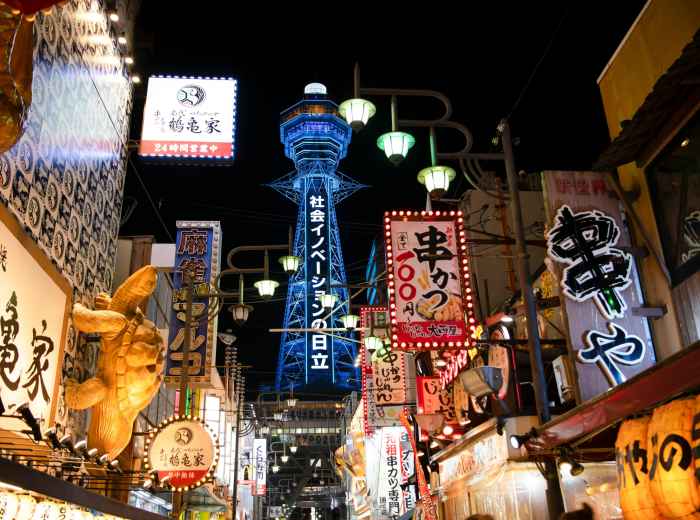 Wide view of Shinsekai’s main street with stacked signs, shops, and people walking under bright storefront lights. Image by David Dibert on Pexels.