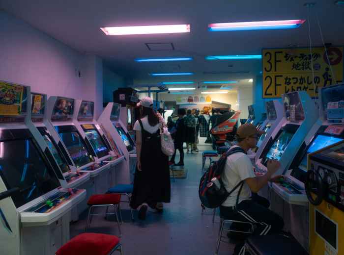 Rows of brightly lit arcade machines inside a Shinsekai gaming center. Image by Gaku Suyama on Unsplash.