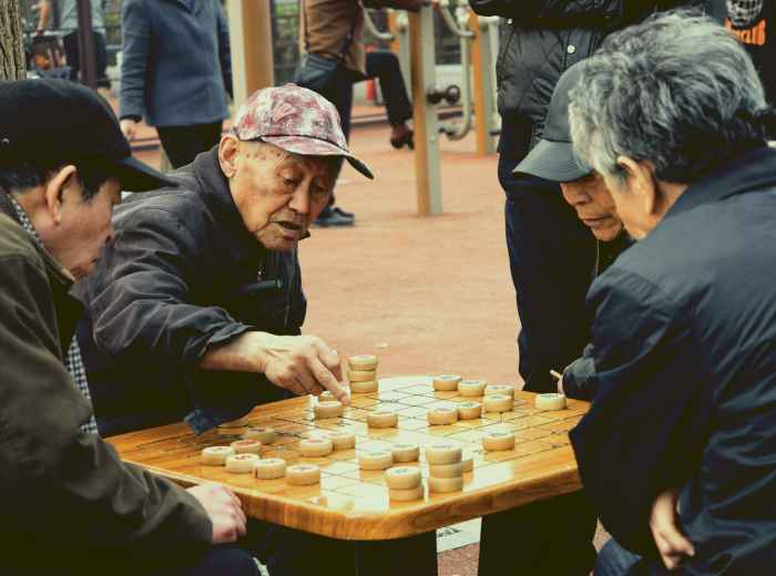 Local man focused on a game of shogi at a small table outside a kushikatsu shop in Shinsekai. Image by Woody Yan on Unsplash.