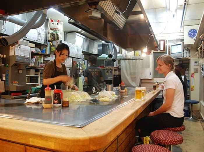 Guests trying okonomiyaki in a local kitchen. Image by Maarten Heerlien from Voorschoten, The Netherlands Creative Commons Attribution 2.0