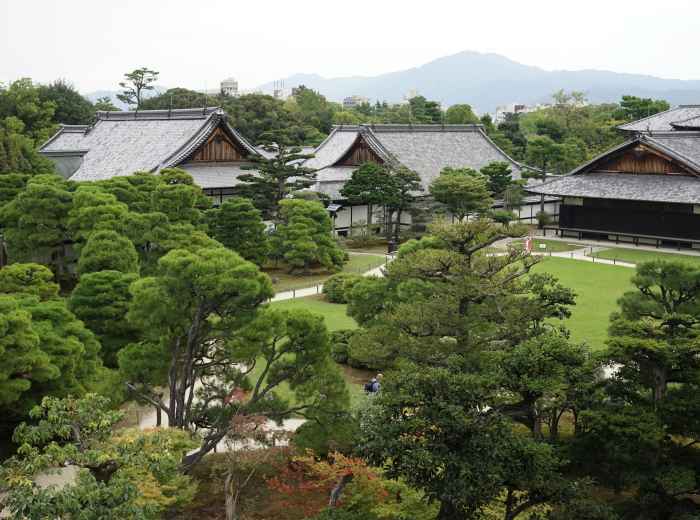 Traditional gardens of Kyoto Imperial Palace with manicured plants and distant mountain views on a clear day. Image by YQ Tian on Unsplash.