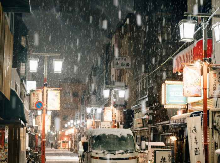  A traditional street scene with wooden buildings, warm light glowing from windows, and light snow beginning to fall Photo by Tsuyoshi Kozu on Unsplash