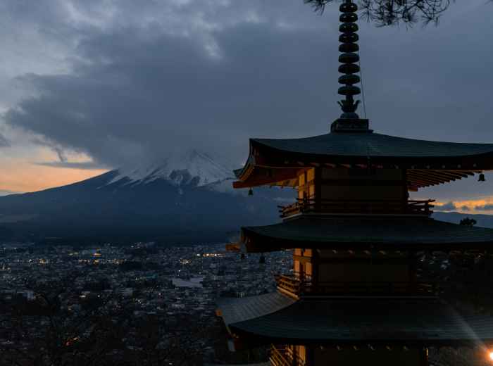 A sunset view over Kyoto with traditional architecture silhouetted against mountains Photo by Nicolas Lindsay on Unsplash