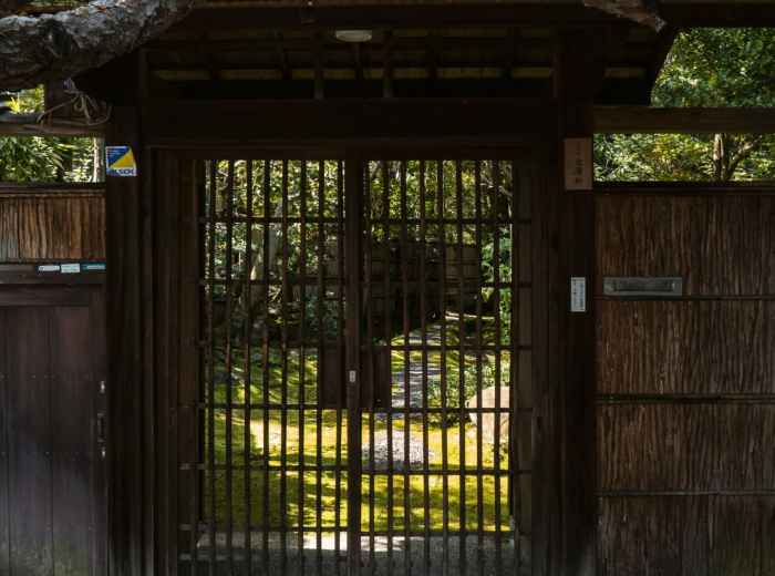 Traditional Japanese house with garden visible through wooden gates. Image by David Emrich from Unsplash