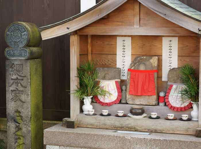 Small neighborhood shrine with fresh offerings and hand-written prayers. Image by zenigame photo from Unsplash