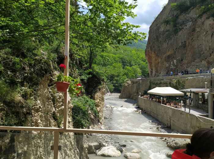 Traditional platform dining over mountain stream with diners enjoying riverside meal Photo by Parvana Mahmudlu on Unsplash