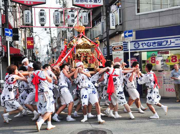 Energetic festival celebration in Osaka with traditional portable shrines and enthusiastic participants
