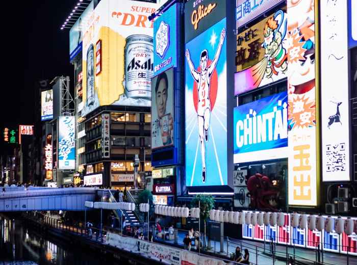 Street scene in Dotonbori with neon signs reflecting in the canal.