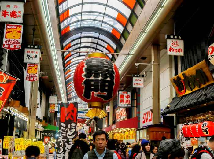 Busy street scene showing multiple food stalls with locals and tourists mingling.