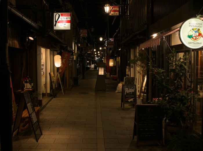Quiet, lantern-lit alleyway in Osaka at dusk with no visible tourists. Photo by Julien on Unsplash