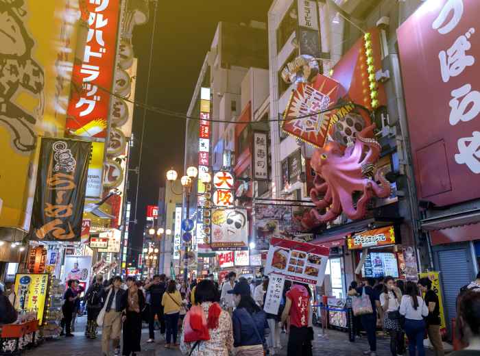 A busy market with vendors, shoppers, and visitors exploring food stalls. 