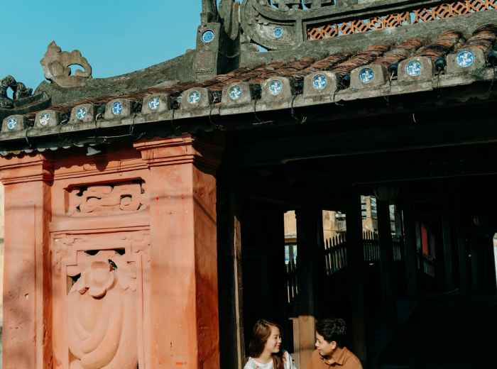A guest and guide sharing a laugh while walking near a temple entrance. Photo by Trần Long on pexels